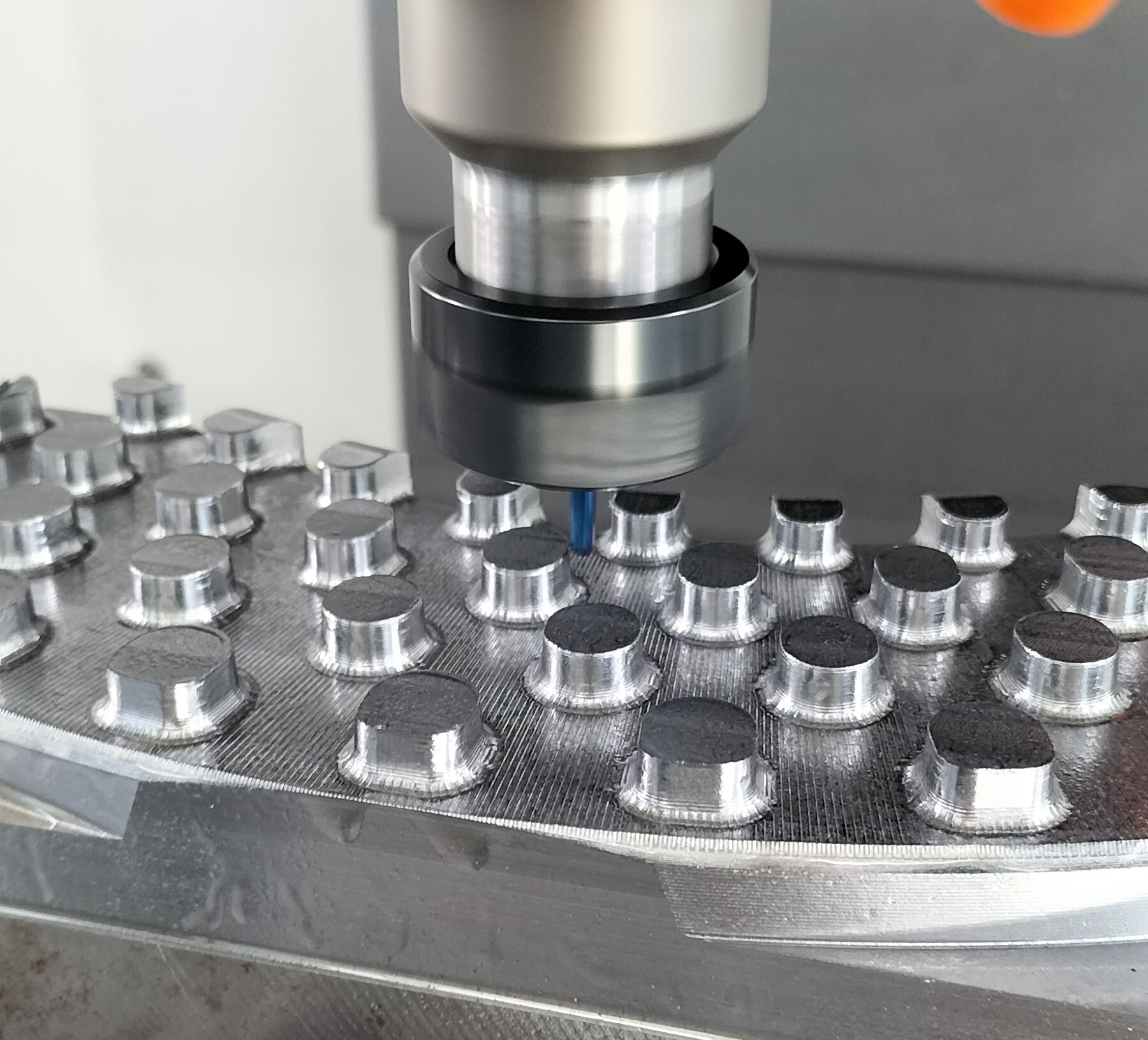 Frästeil in der CNC-Fräsmaschine, der Fräser ist gerade im Eingriff und bearbeitet das Metallbauteil. Die präzise Bearbeitung wird in Echtzeit ausgeführt.