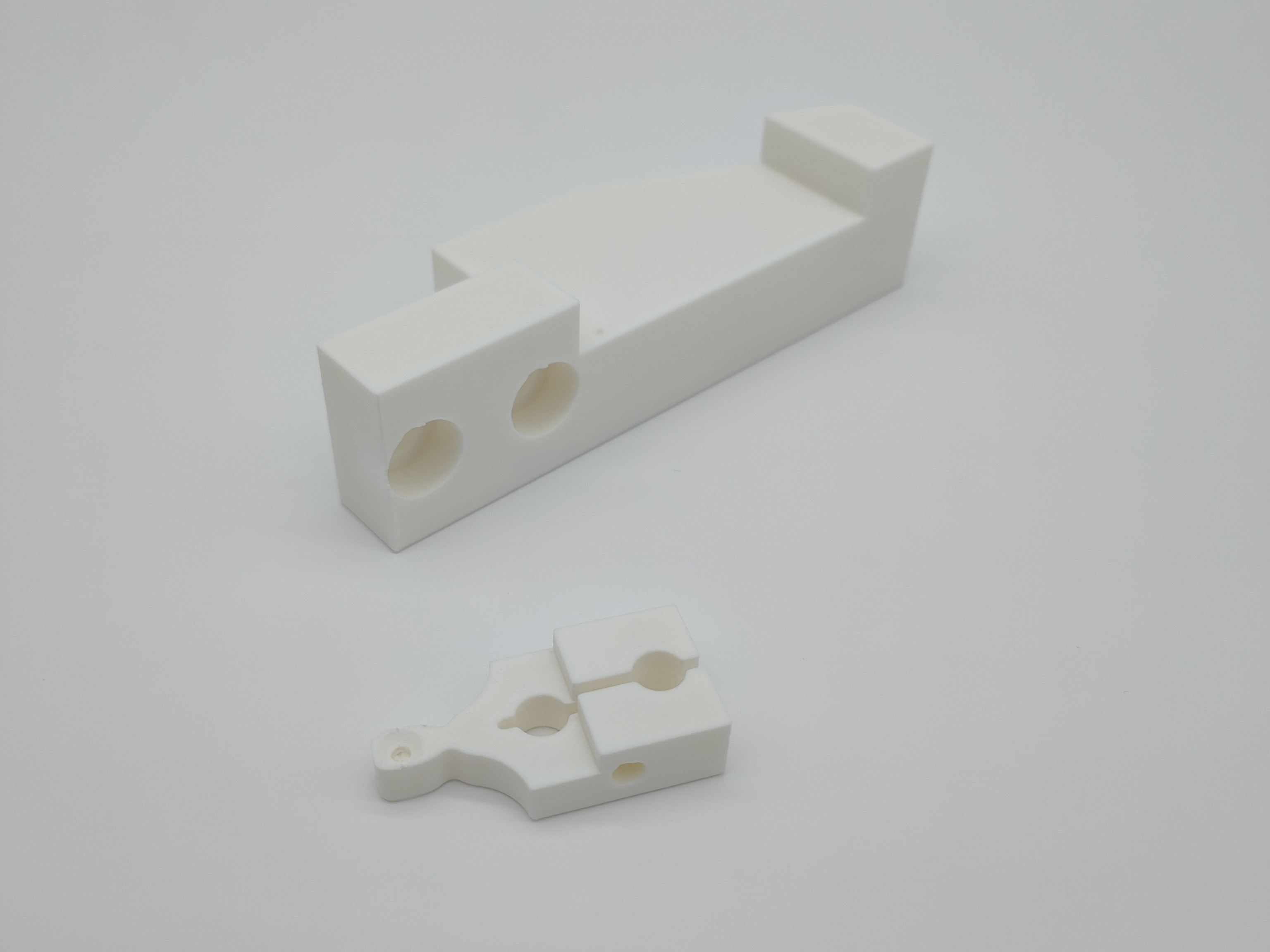 Zwei weiße 3D-gedruckte Prototypenteile aus PLA auf neutralem, weißem Hintergrund. Präzisionsdruck für technische Anwendungen im Prototypenbau.